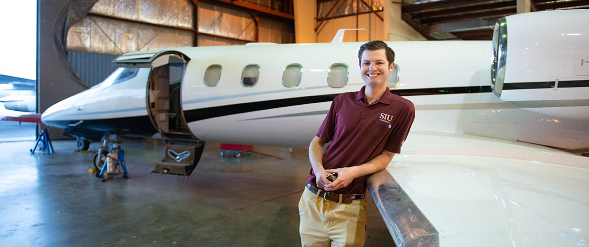 SIU Aviation Management Student Stands in front of a Plane