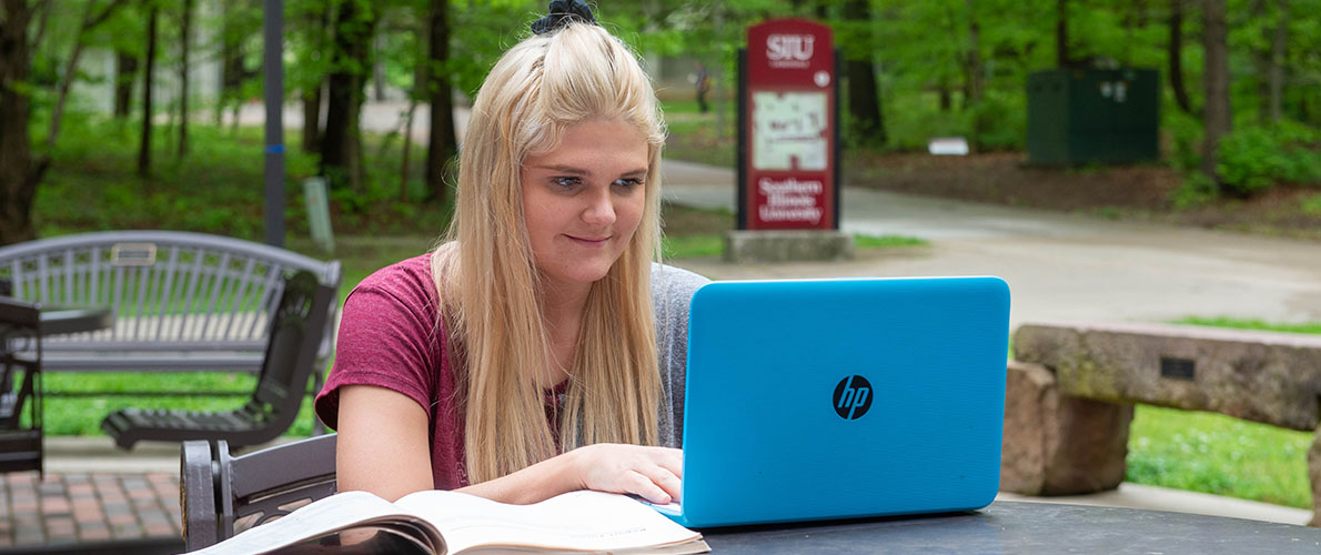 SIU Communication Studies student studying outside with computer.