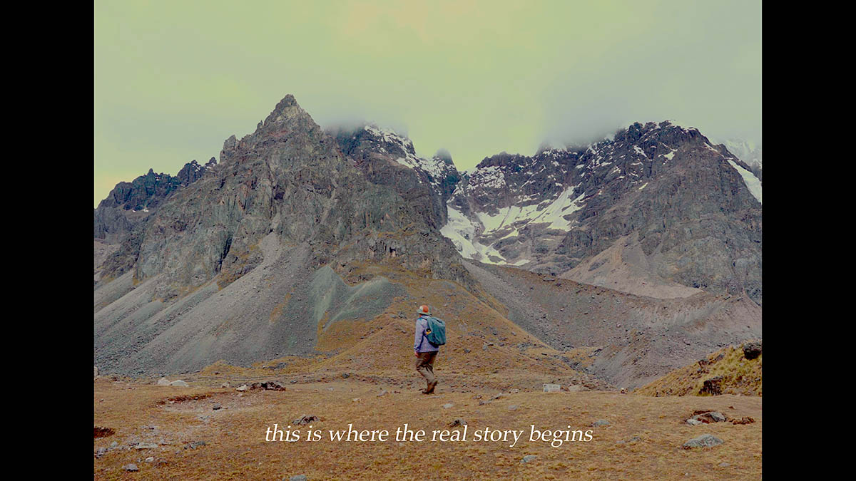 A hiker looks at a mountainside with text This is where the real story begins