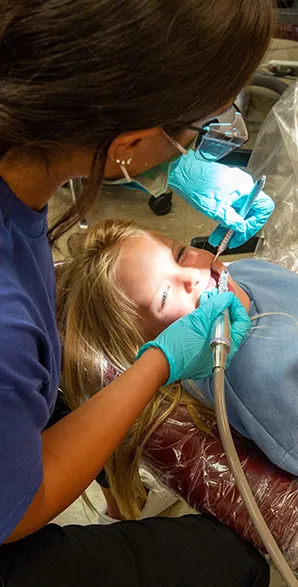 SIU Dental Hygiene student works on a smiling girl in the Clinic