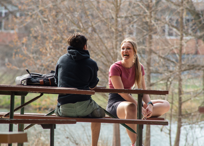 SIU students sitting at a picnic table laughing together on campus
