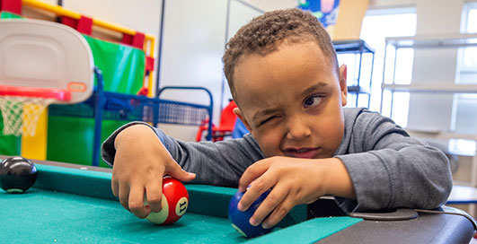 Young Boy plays pool in SIU's Autism Lab 