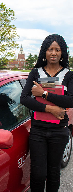 SIU Social Work student by car with Pullium Hall in the background