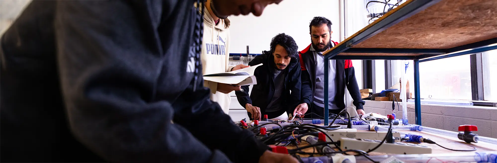 Students work with wiring and sensors on a research apparatus in an engineering laboratory.